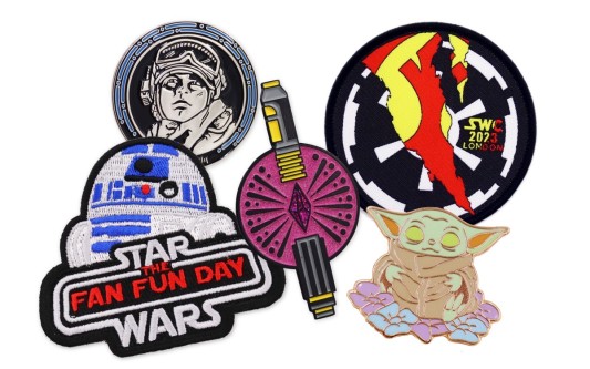 A collection of Star Wars pins and patches featuring Master Yoda, Luke Skywalker, R2D2, and Lightsabers.