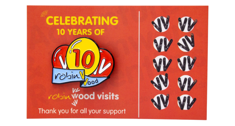 Custom enamel pin badge celebrating 10 years of Robin Wood visits, displayed on a red commemorative backing card.