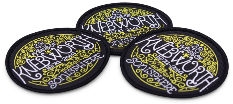 Three black embroidered Knebworth anniversary patches featuring white lettering and yellow decorative swirls and patterns.