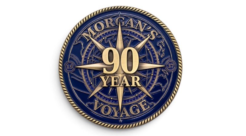 Blue and antique gold 90-year anniversary challenge coin for Morgan's Voyage, featuring a compass design and raised lettering.