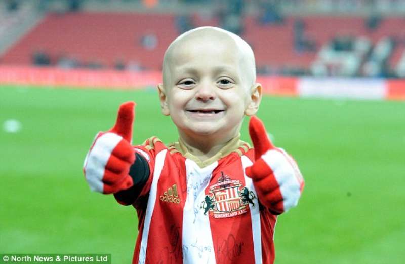 Bradley Lowery attends a Sunderland game. On the pitch, he gives a gloved two thumbs up alongside his trademark cheeky smile.
