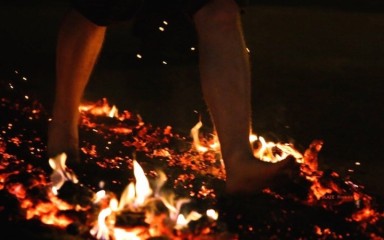 A barefooted fore walker saunters across red hot coals.