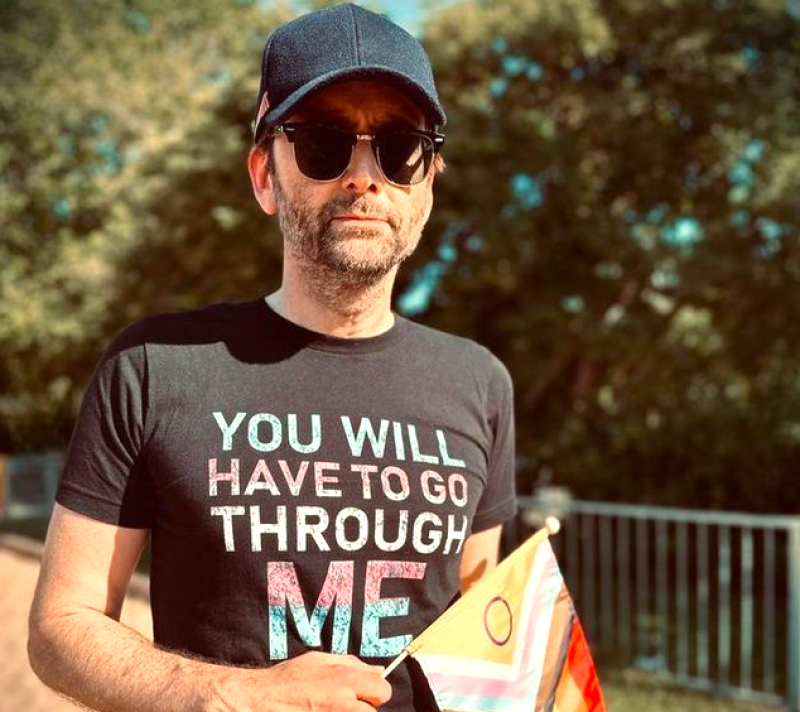 David Tennant wearing a blue baseball cap and a grey t-shirt with the slogan
