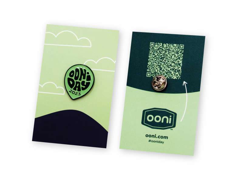 A green balloon-shaped pin badge that says 