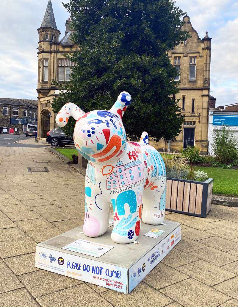 A cartoon Snowdog statue colourfully painted outside Huddersfield town hall.