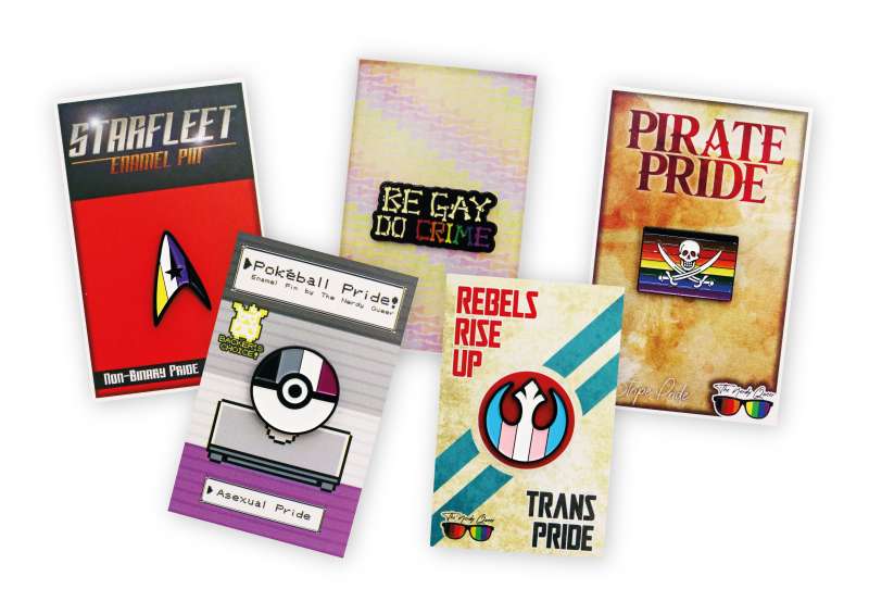 Five Pride and LGBTQ+ enamel pins and their backing cards. Themes revolve around Star Trek, Start Wars, Pokemon, & Pirates.