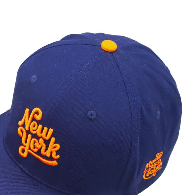 A top-down photo of a blue baseball cap showcasing the bright orange cap button.