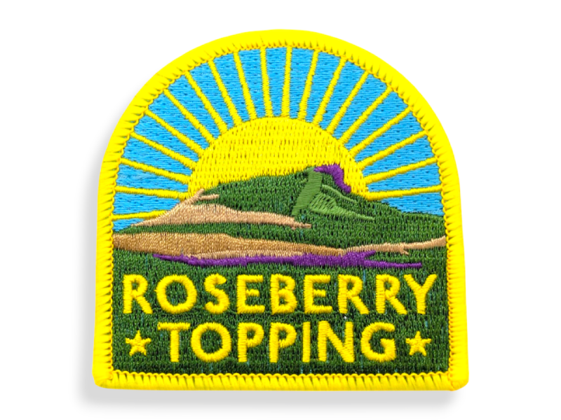 A colourful embroidered walking patch featuring a sunny hillside design and a yellow overlocked edge.