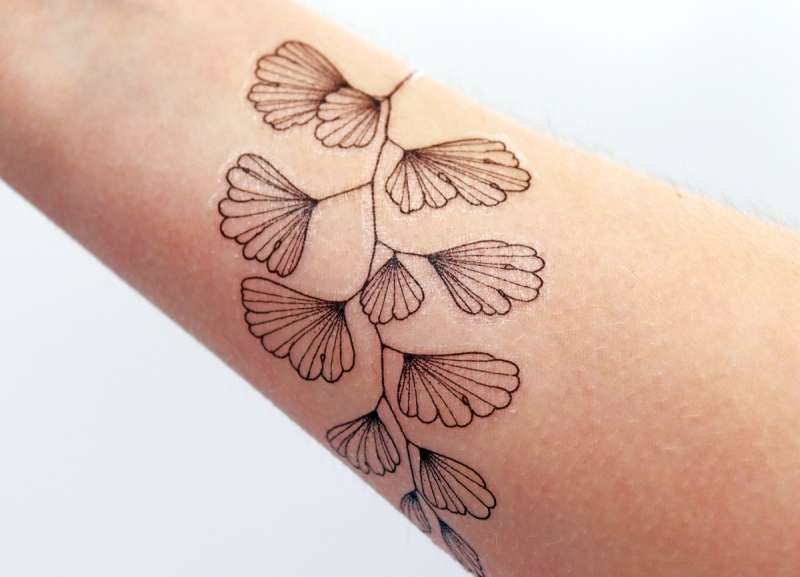 A delicate plant leaves temporary tattoo has been perfectly applied to hairless arm.