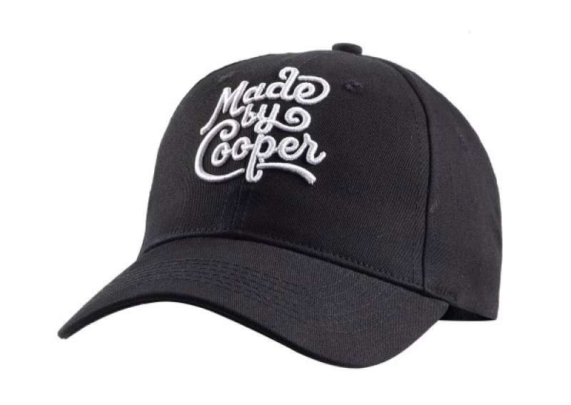 A black baseball cap with the Made by Cooper logo embroidered on the front in white thread.
