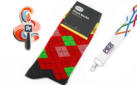 A set of branded merch. A custom pin badge, branded socks, and corporate lanyard.