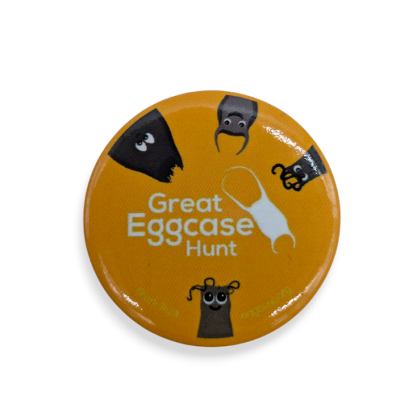 A yellow bespoke button badge featuring the logo, branding, and text for