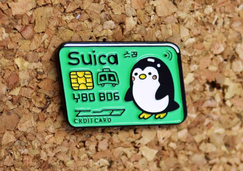 A pin badge that looks like a cartoon credit card with a cute penguin on it.