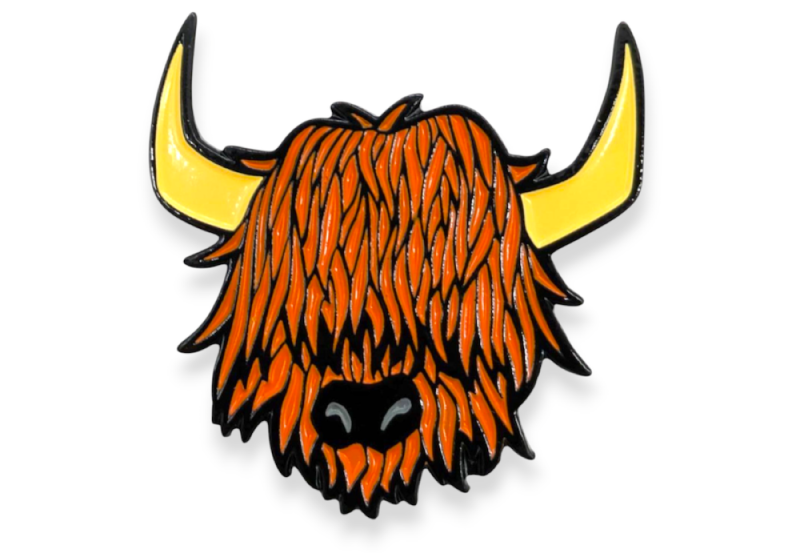 A soft enamel pin badge of a highland cow's head. The cow has orange hair and yellow horns.