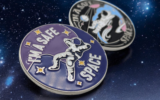 Two custom trans pin badges featuring the logo for Stevie's Safe Space, an organisation that focuses on helping transgender people across the world.