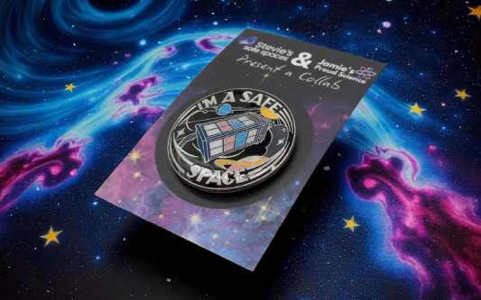 circular pin badge with a TARDIS in the middle made up of the trans pride flag colours. Around the TARDIS reads the words