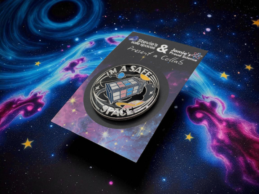 circular pin badge with a TARDIS in the middle made up of the trans pride flag colours. Around the TARDIS reads the words