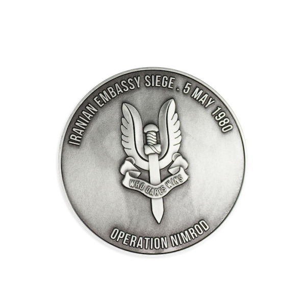 A challenge coin with the iconic winged dagger emblem of the SAS in the middle with the words