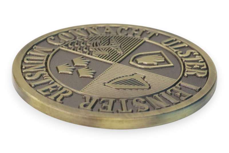 Die-struck custom coin with engraved crest design, showing flat surface and clean lines for a traditional finish.