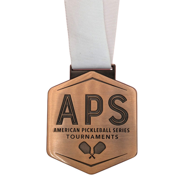 A bronze coloured American Pickle Ball medal attached to a bright white ribbon.