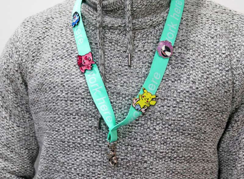 A person wearing a lanyard displaying a collection of four different Pokemon pin badges. Pickchu, Bulbasaur, Gastly, and Squirtle wearing a Sailor Moon costume.