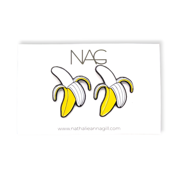 A pair of soft enamel banana earrings attached to a whote earring backing card.