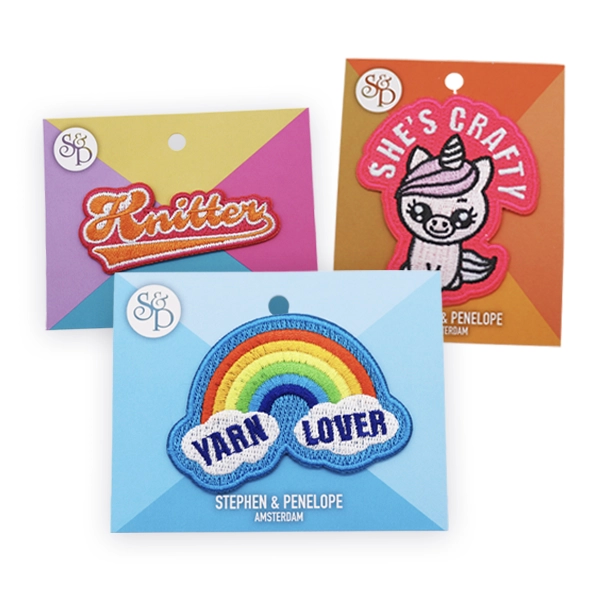 Selection of colourful custom embroidered patches displayed on branded backing cards, including rainbow, unicorn and text designs, showcasing detailed embroidery suitable for retail, gifts or personalised embroidered patch collections.
