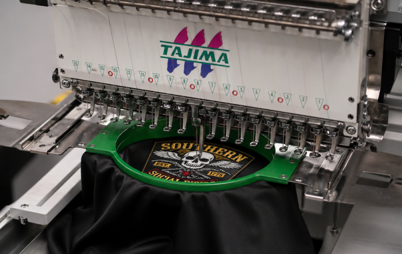 Industrial embroidery machine stitching a custom patch design onto fabric showing how embroidered patches are produced.