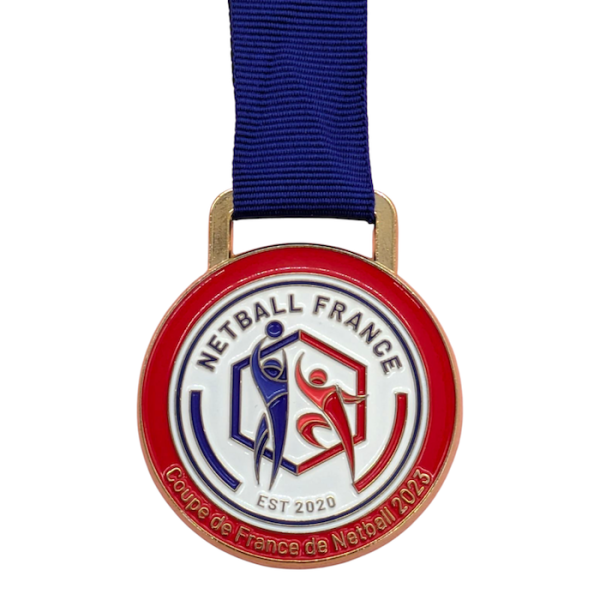 A circular custom enamel medal with red edges and a geometric pattern that looks like people playing netball. The medal reads