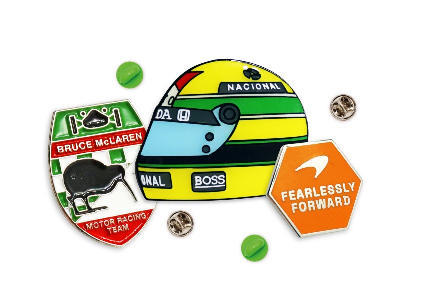 F1 Custom Merch - An Aryton Senna vintage f1 helmet pin badge, a Bruce McLaren long service award badge, and McLaren's Fearlessly Forward branding enamel pin.