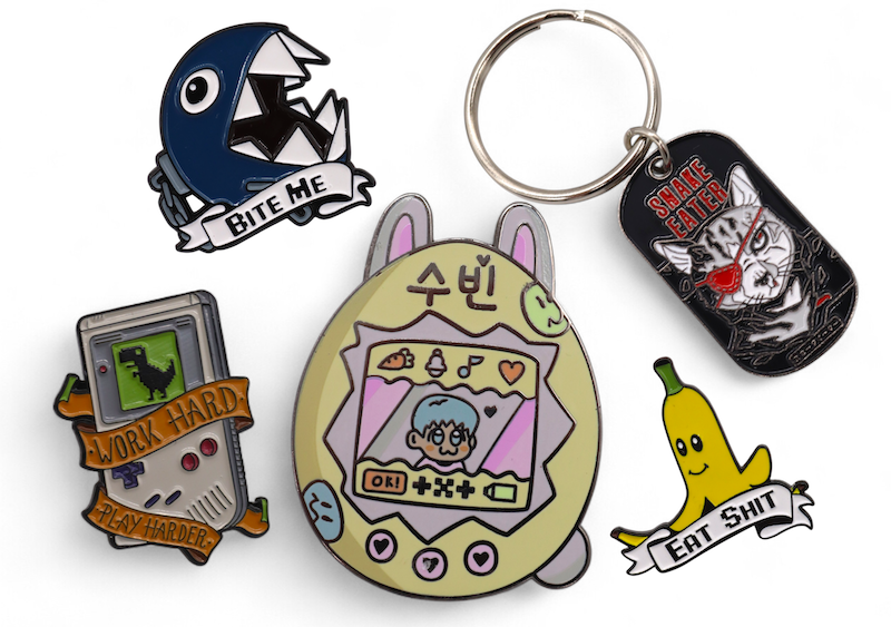 Collection of colourful fan-created video game pins and keyrings including characters and retro designs.