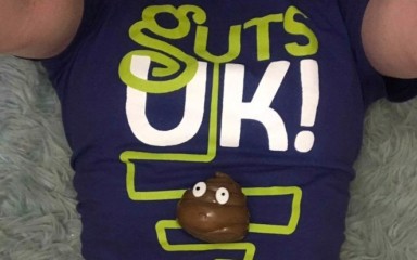 Someone laying on their back wearing a Guts UK branded T-shirt and a plastic poo balancing on their stomach ... at least I hope it's plastic!