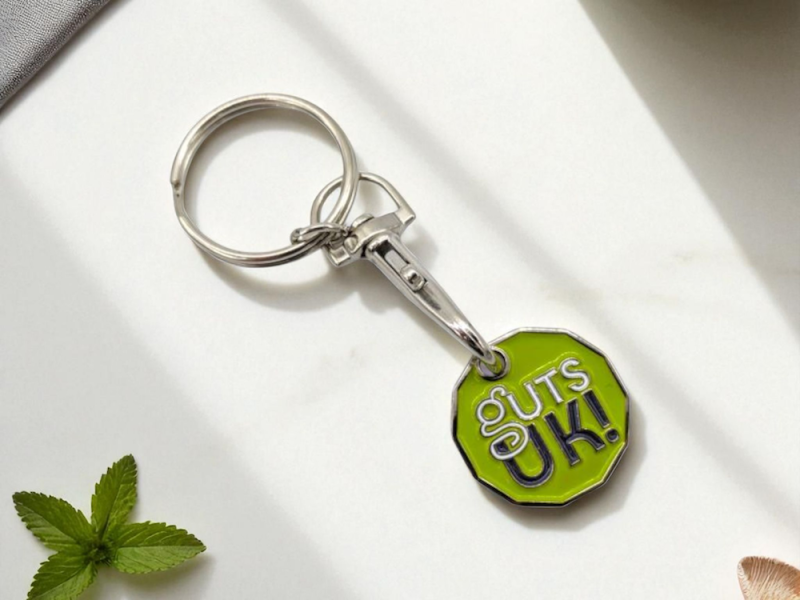 A green branded trolley token keyring baring the Guts UK logo.
