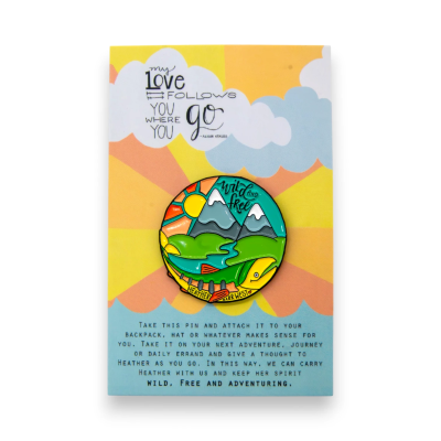 Illustrated mountain landscape pin badge displayed on a memorial backing card, showing how custom pin badges for designers and illustrators can tell a personal story.
