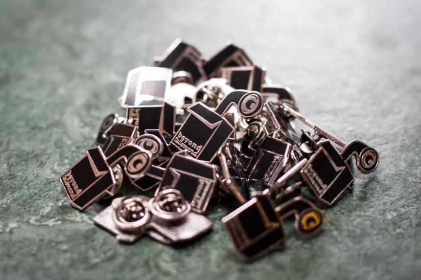 A pile of black and gold pin badges.