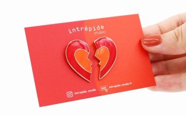 A broken heart pin badge on a red backing card