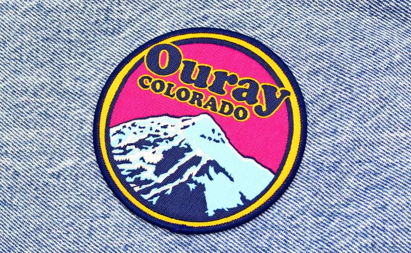 A colourful Ouray Colarado iron-on patch stuck to a piece of denim.