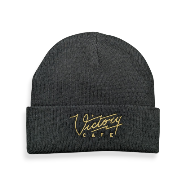 A custom beanie hat made from black fabric and gold thread embroidered logo.