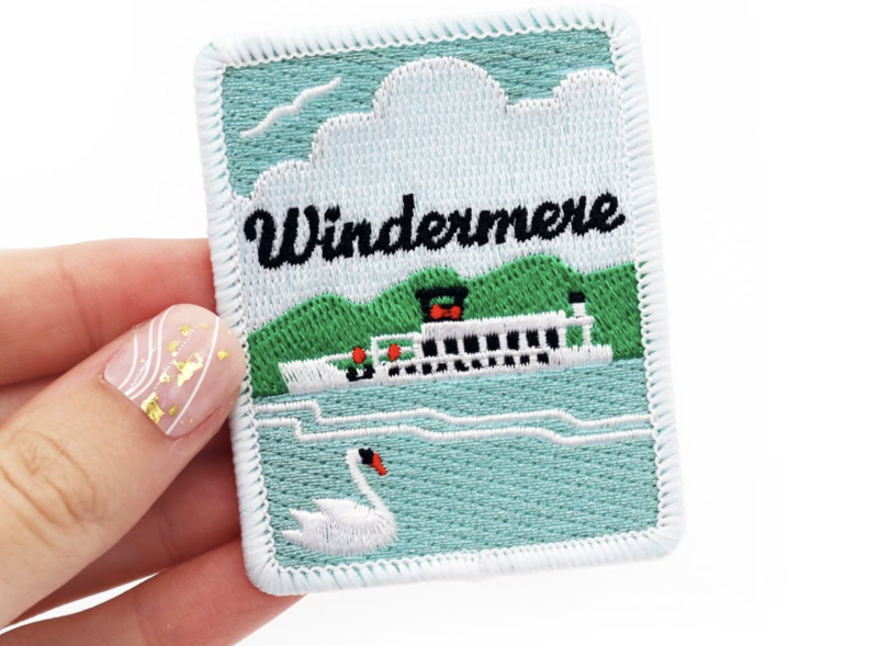 Close-up of embroidered patch showing thread texture, stitched lettering and layered design detail on fabric backing.