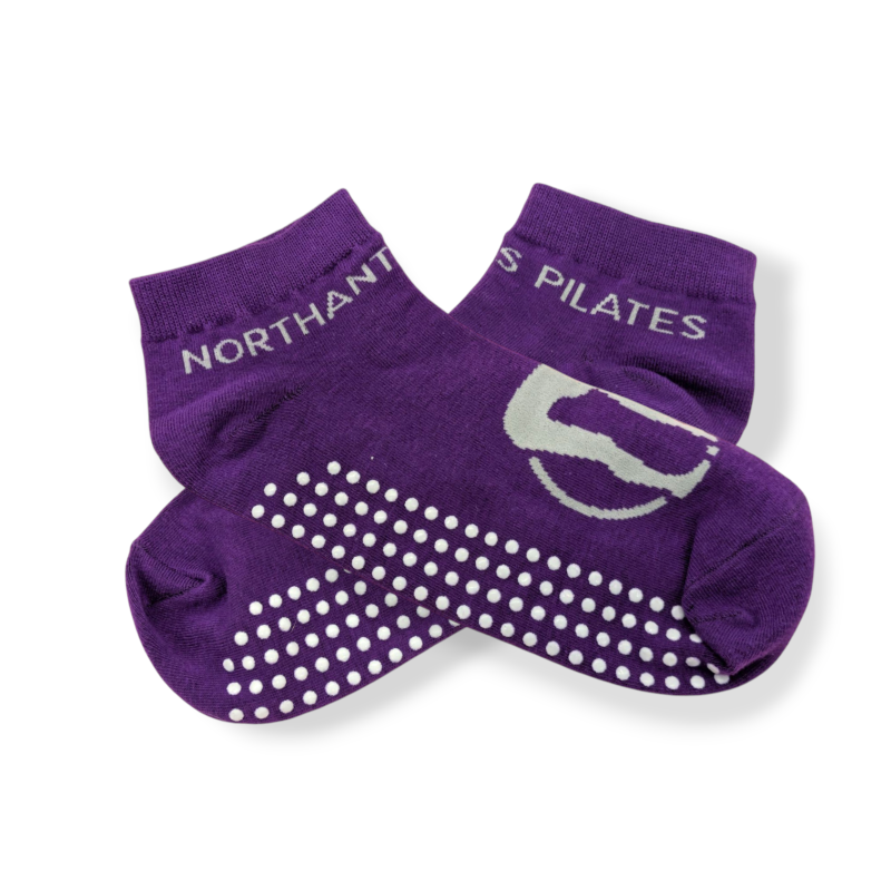 A pair of purple pilates socks with white spotty grips on the sole and