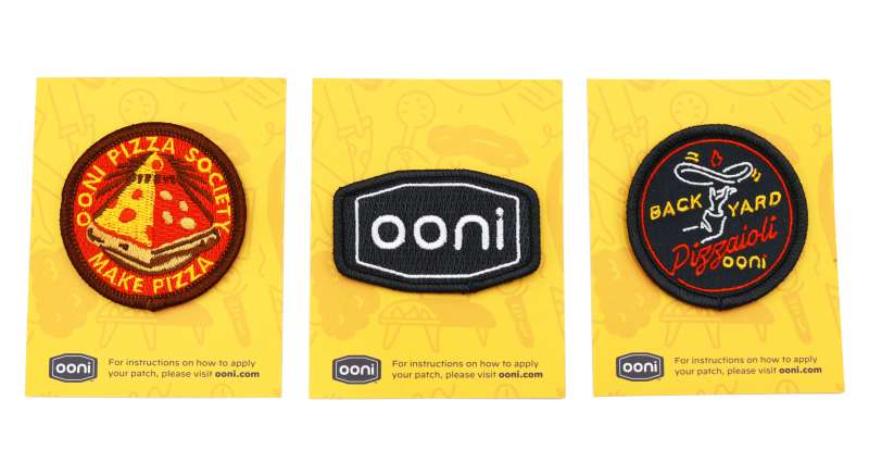 Three embroidered patches featuring the Ooni logo, a slice of pepperoni pizza made to look like the illuminati logo, and a patch that says 