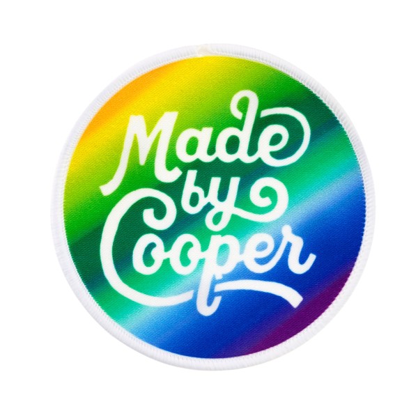 Printed patch with a rainbow colour gradient and the Made by Cooper logo in white.