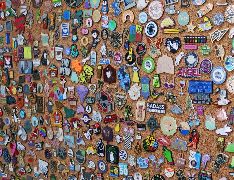 A massive pin badge collection being display on a corkboard.
