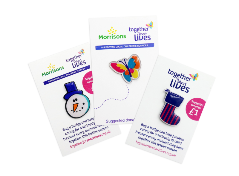 Three charity pin badges on white backing cards to support the