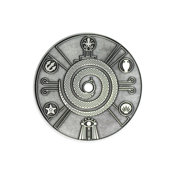 An antiqued silver-plated coin featuring Eygptian icons and drawings around the outside of a curled up snake.