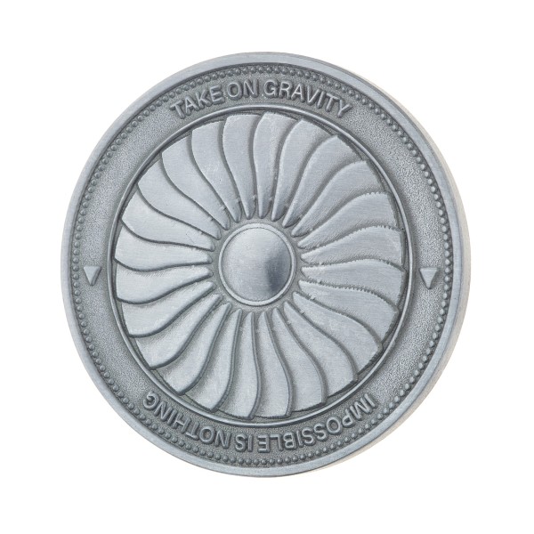 A silver looking custom coin features a large turbine fan and the words