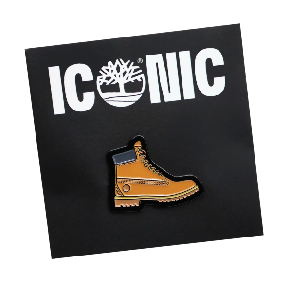A custom soft enamel pin badge shaped like a rugged brown Timberland boot, complete with stitching effects, enamel shading and raised metal outlines, designed for fashion brands, outdoor inspired merchandise and high quality custom pin badge collections.
