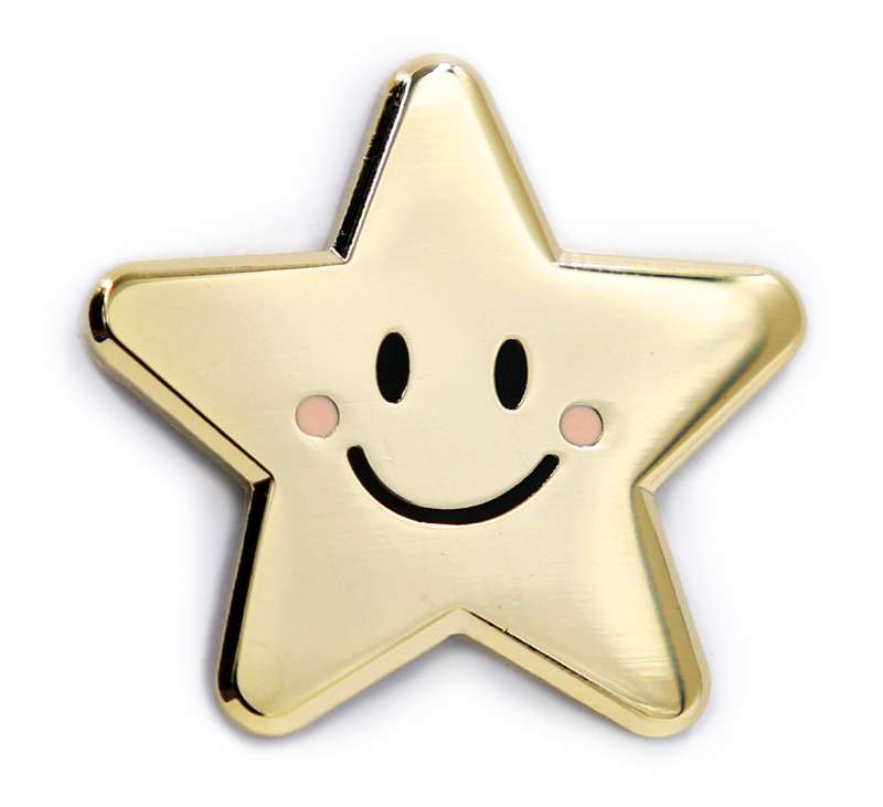 A gold-plated pin badge of a tiny gold star with a simple smile and eyes and pink rosy cheeks.
