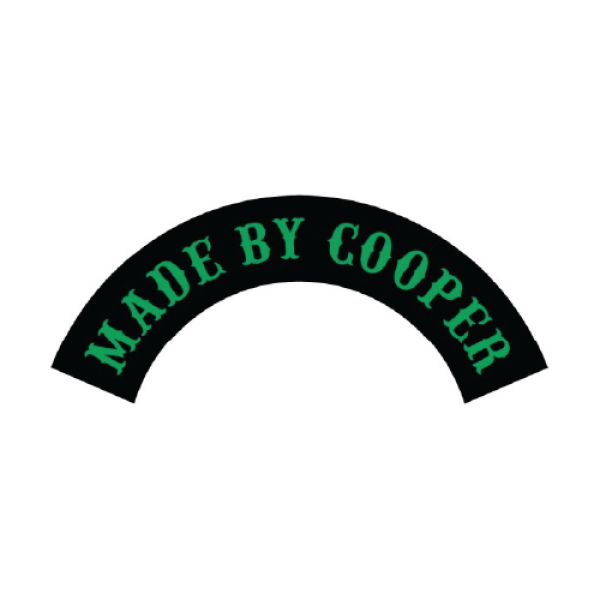 A black rocker biker patch with red text that says Made by Cooper in green thread.