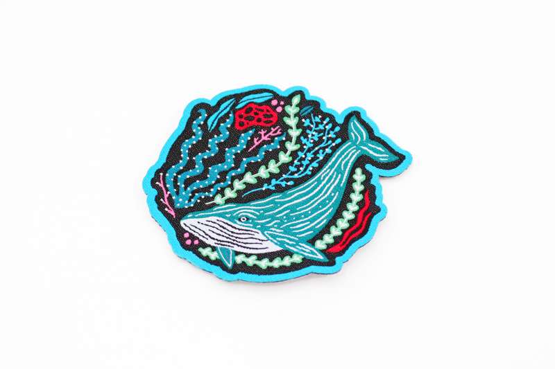 A stunning whale iron-on patch with vibrant blue ocean fauna and a teale whale.